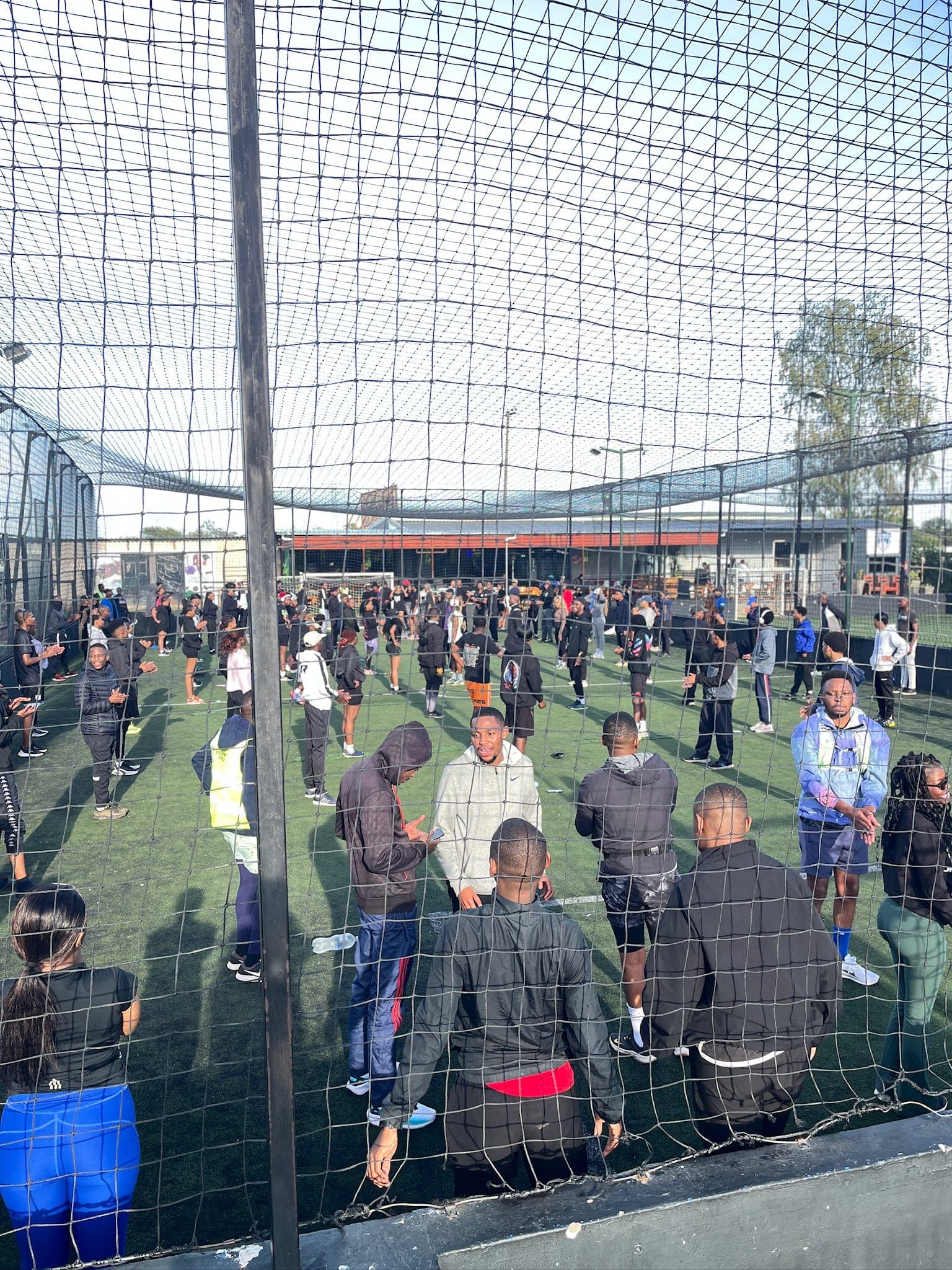 A large Pace Day crowd filling the turf pitch, seen through the perimeter netting