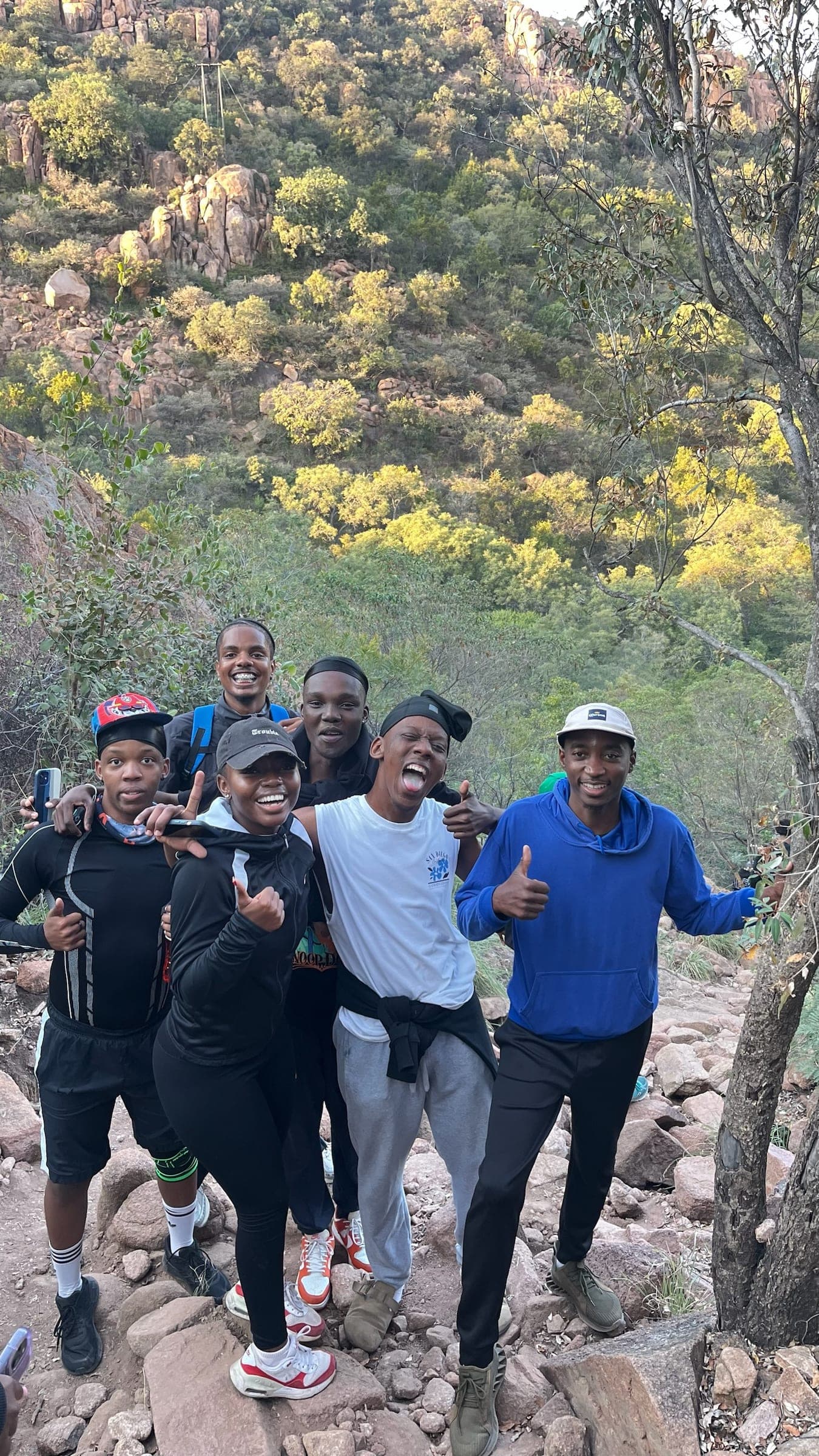 Hikers stopping for a photo on a rocky trail with a green hillside behind them