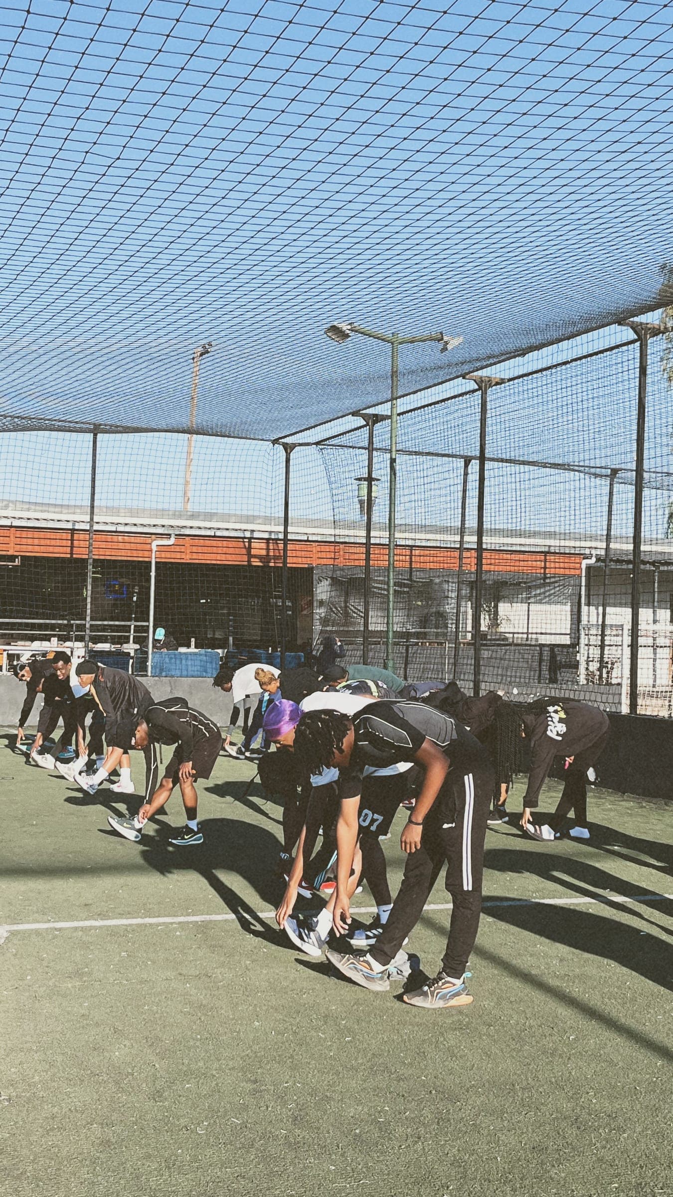 A line of runners bent forward in a hamstring stretch across the turf